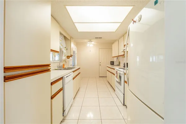 a large white kitchen with granite countertop a sink and dishwasher a stove with wooden floor