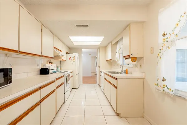 a kitchen with a sink a stove top oven and white cabinets