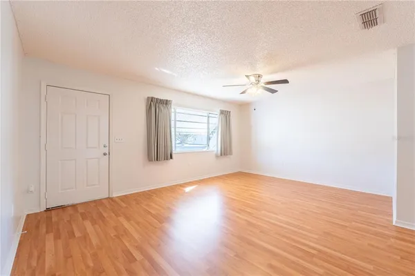 a view of a room with wooden floor and a ceiling fan