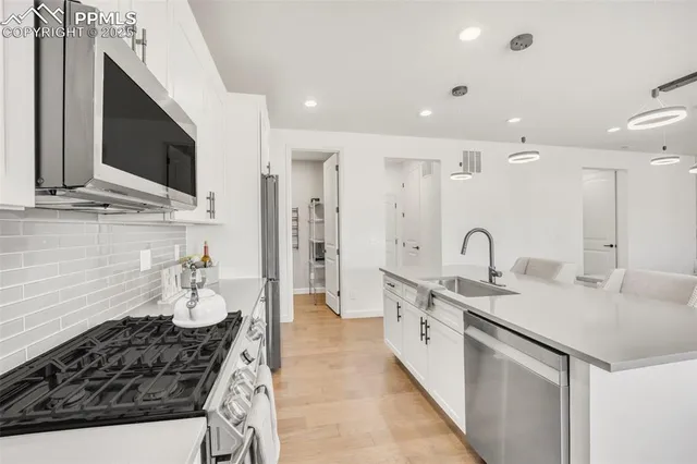 a large kitchen with stainless steel appliances a stove a sink a refrigerator and a microwave