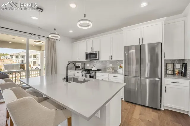 a kitchen with stainless steel appliances granite countertop a refrigerator a stove a sink a dining table and chairs