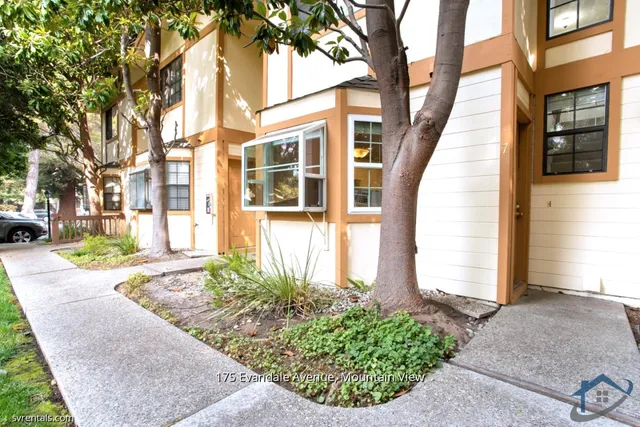 a view of a brick house with many windows next to a road