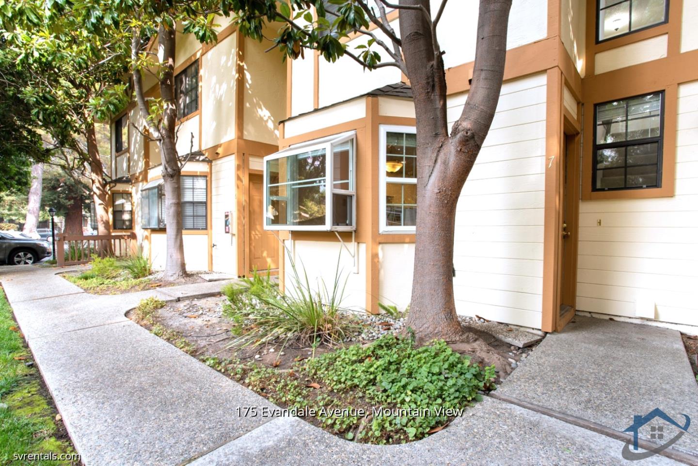 a view of a brick house with many windows next to a road