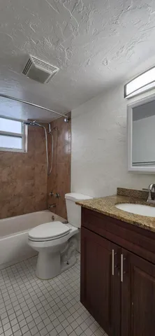a bathroom with a granite countertop toilet a sink and a bathtub