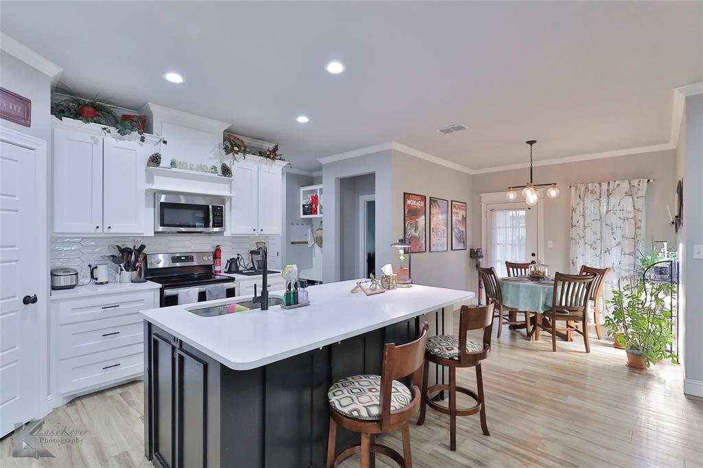7329 Mountain View Road Abilene, TX 79602 - Photo 10 of 33 a kitchen with stainless steel appliances kitchen island granite countertop a dining table chairs and white cabinets