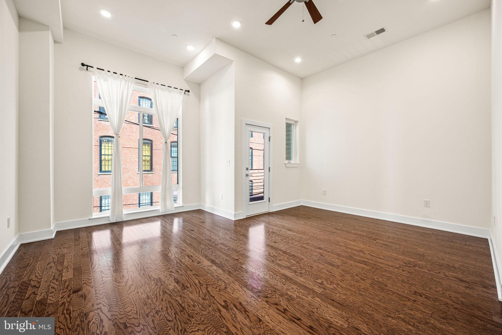 1115 North American Street, Unit D5 Philadelphia, PA 19123 - Photo 11 of 52 a view of an empty room with wooden floor and a window
