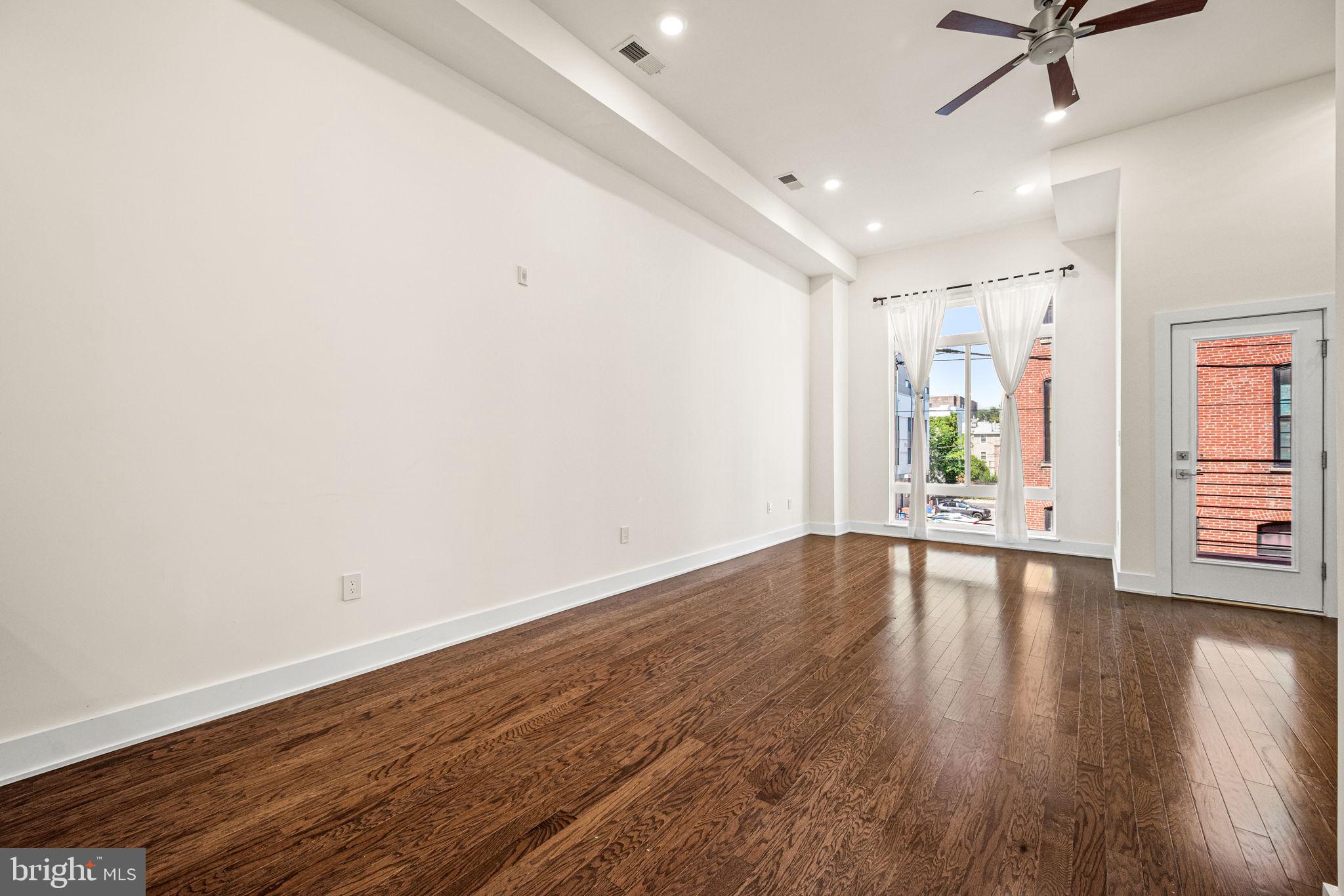 1115 North American Street, Unit D5 Philadelphia, PA 19123 - Photo 17 of 52 a view of an empty room with wooden floor and a window