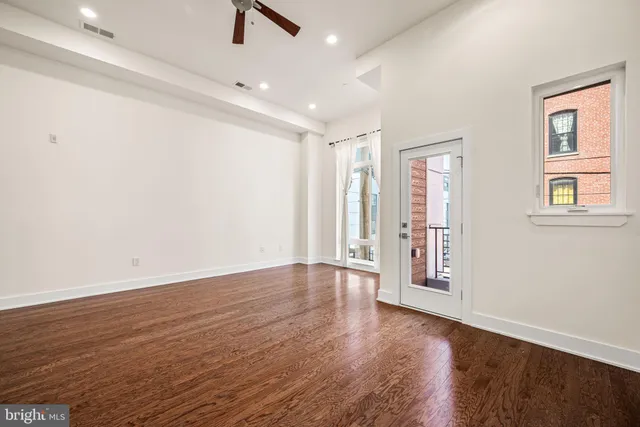 an empty room with wooden floor and windows