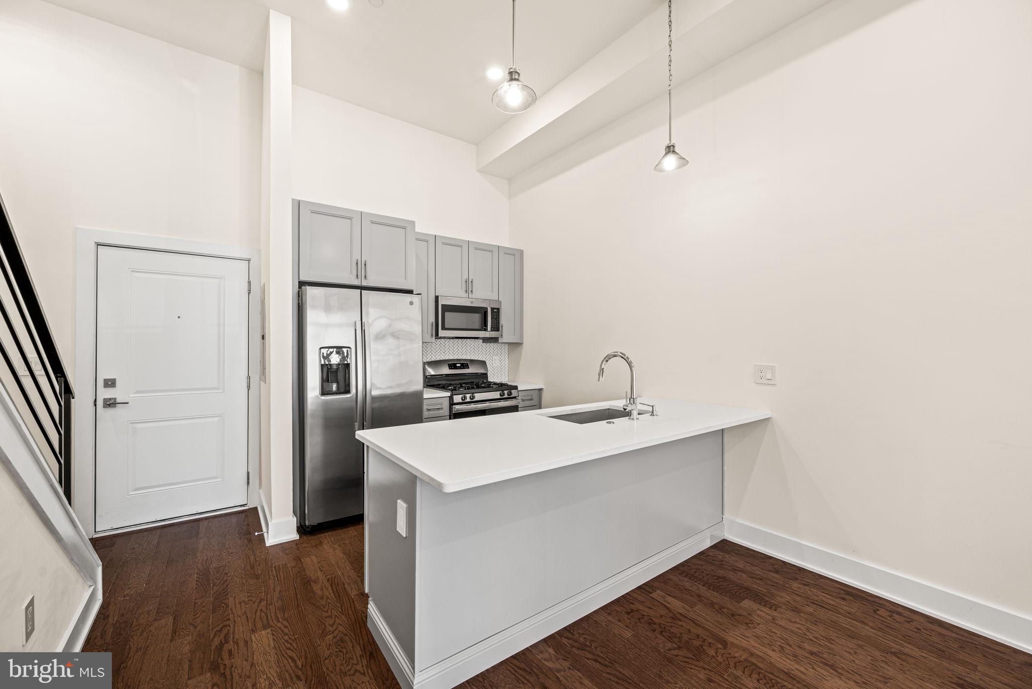1115 North American Street, Unit D5 Philadelphia, PA 19123 - Photo 7 of 52 a kitchen with kitchen island a sink appliances and cabinets