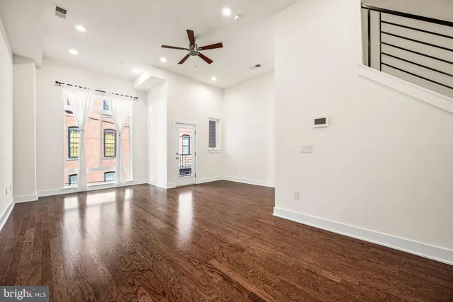a view of an empty room with window and wooden floor