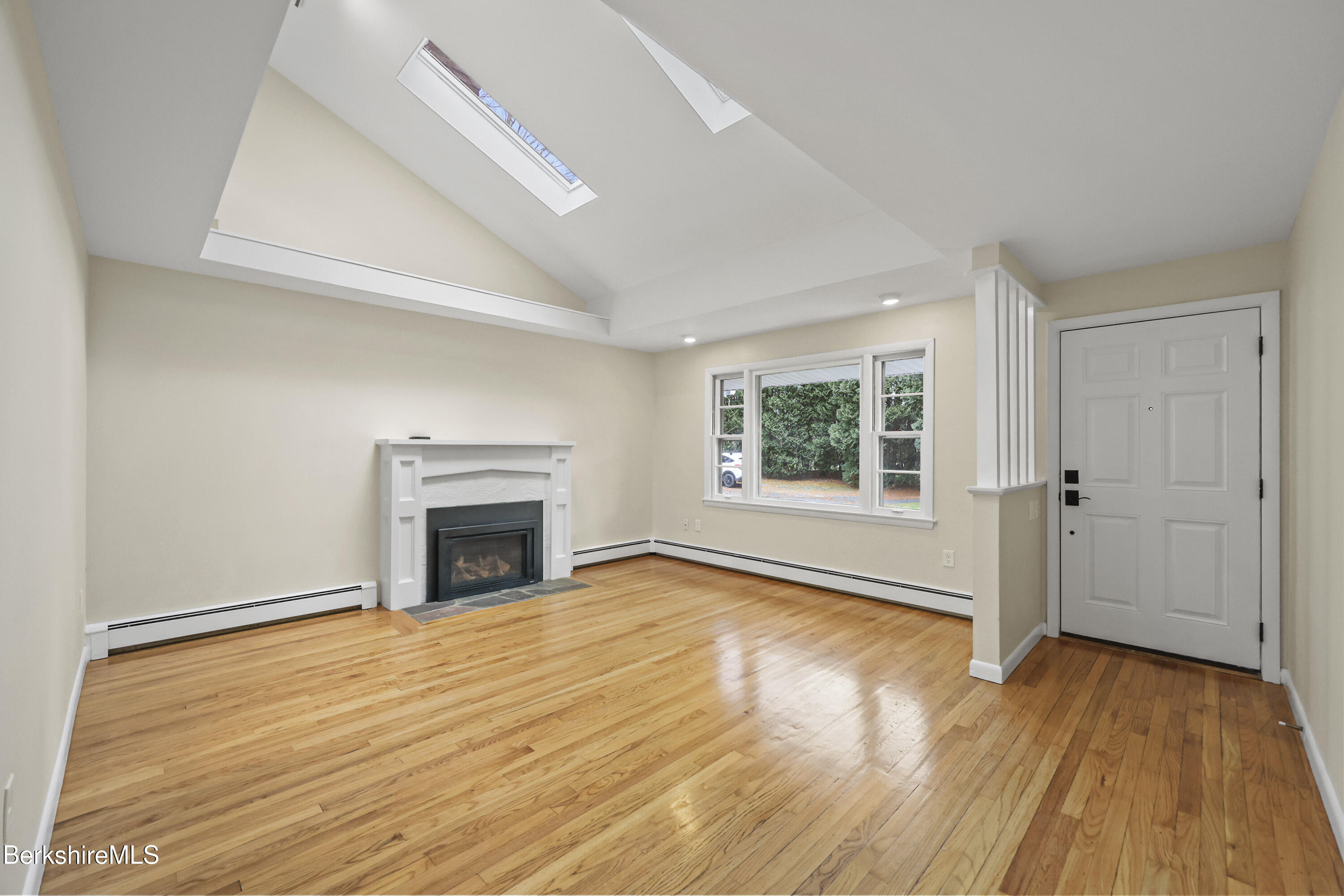 627 Lenox Road Richmond, MA 01254 - Photo 11 of 37 an empty room with wooden floor fireplace and windows