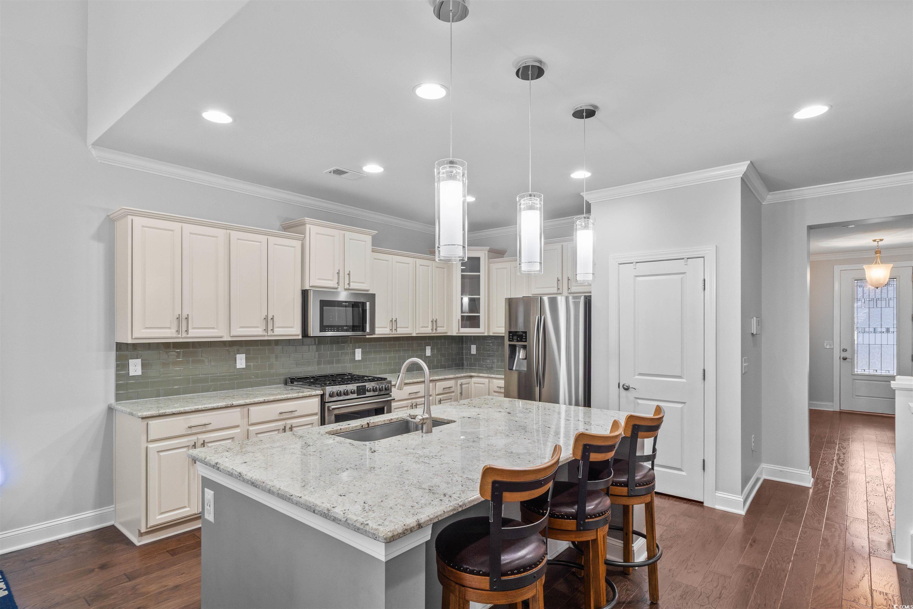 1141 Bronwyn Circle North Myrtle Beach, SC 29582 - Photo 12 of 40 Kitchen with a kitchen breakfast bar, pendant lighting, crown molding, stainless steel appliances, and light stone counters