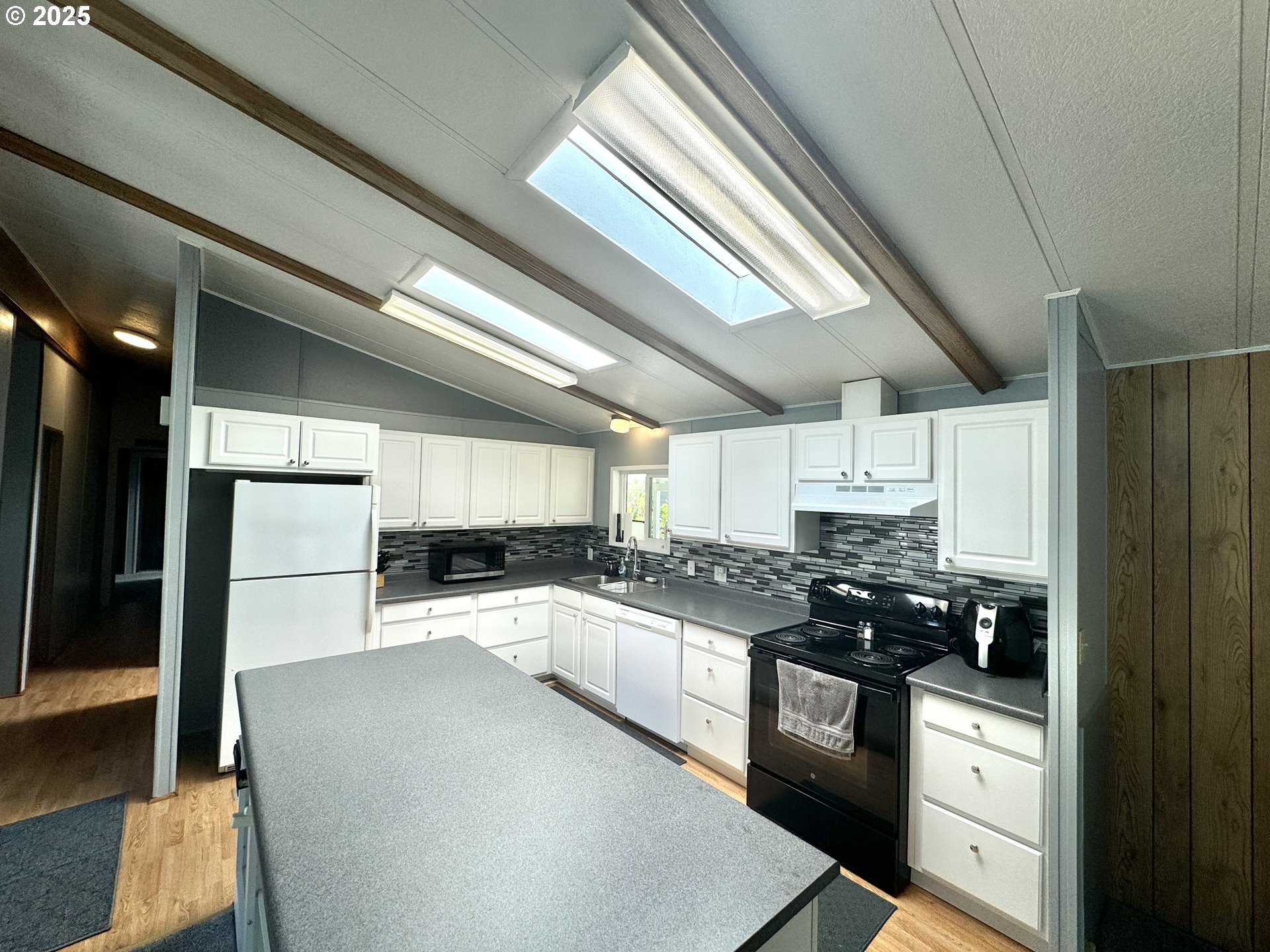 1601 Rhododendron Drive, Unit 676 Florence, OR 97439 - Photo 11 of 36 a kitchen with stainless steel appliances granite countertop a sink a stove a refrigerator cabinets and a window