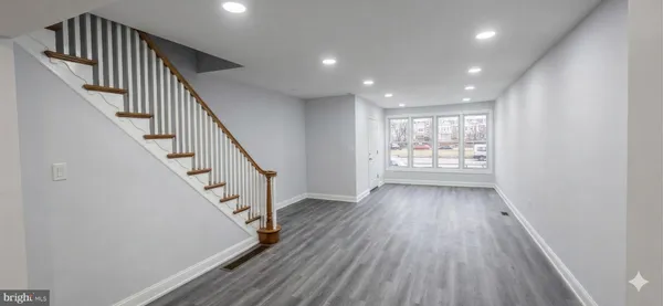 an entryway in a hall with wooden floor and stairs