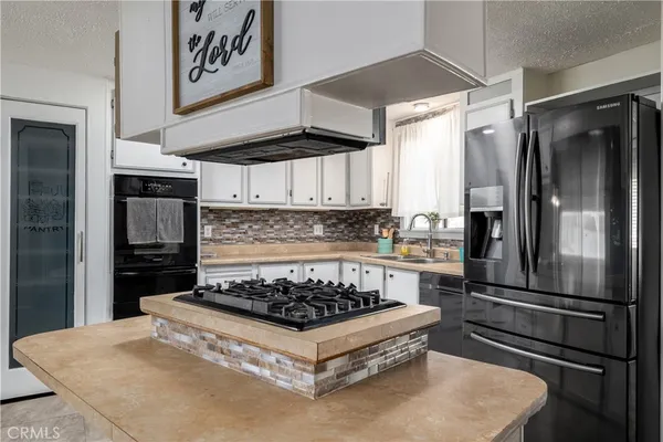 a kitchen with stainless steel appliances granite countertop a refrigerator a stove and a sink
