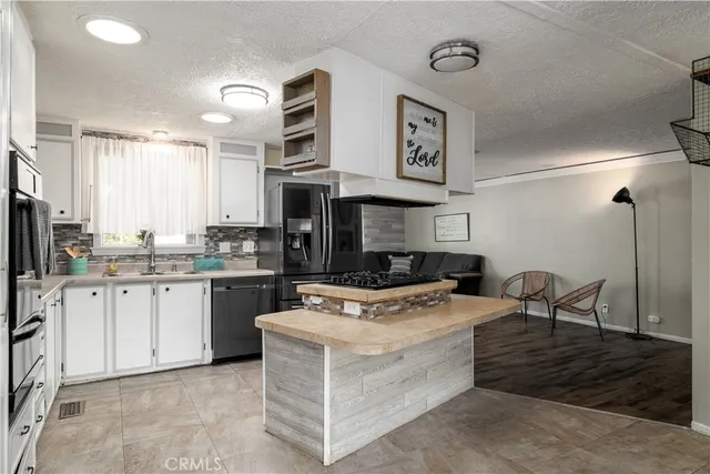 a kitchen with stainless steel appliances granite countertop a stove top oven a sink a dining table and chairs