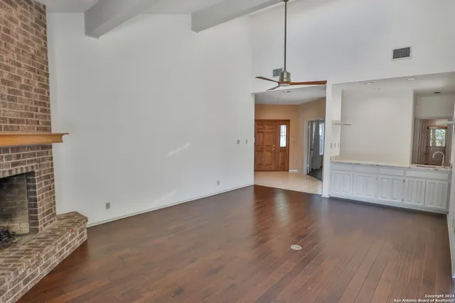 a view of an empty room with wooden floor and a fireplace