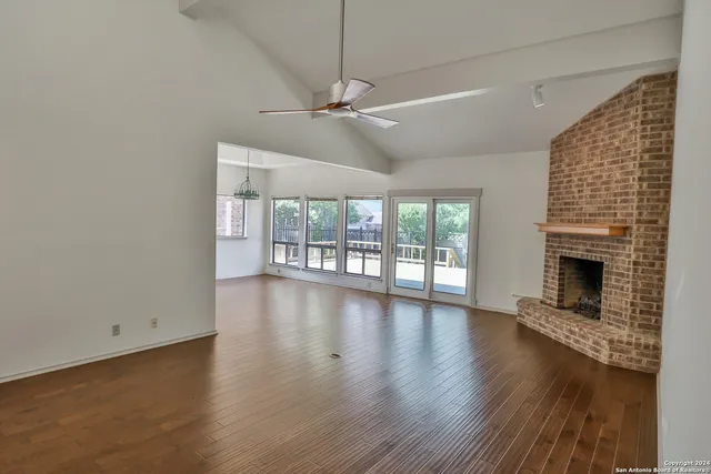 an empty room with wooden floor fireplace and windows