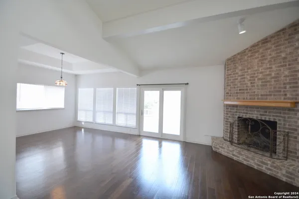 an empty room with wooden floor fireplace and windows