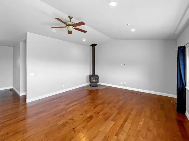 a view of a room with wooden floor a ceiling fan and a window