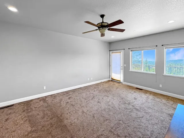 an empty room with windows and fan