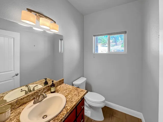 a bathroom with a granite countertop sink toilet and a mirror