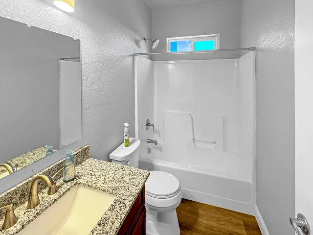 a bathroom with a granite countertop bathtub sink vanity mirror and toilet