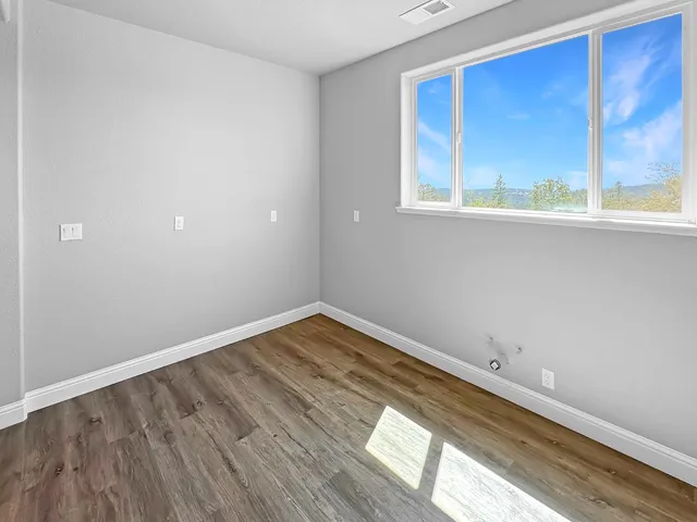a view of empty room with wooden floor and fan