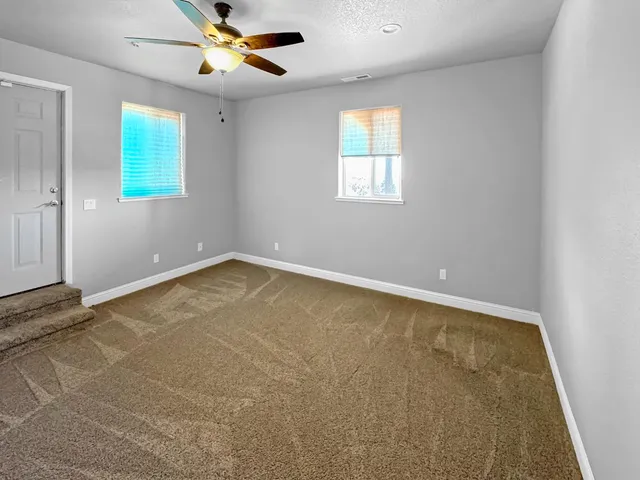 an empty room with windows and fan