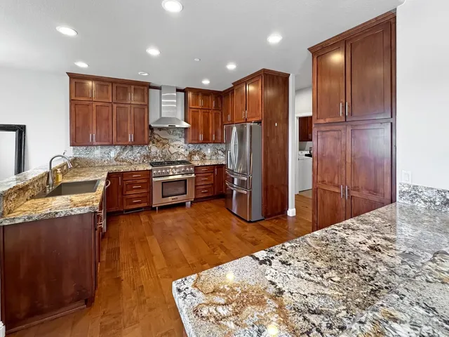 a kitchen with stainless steel appliances kitchen island granite countertop a refrigerator and a stove top oven