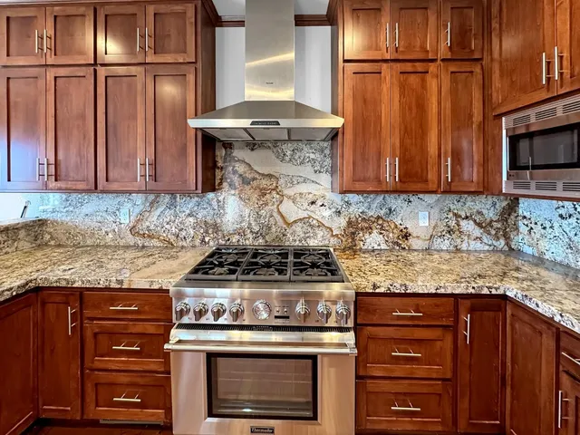 a kitchen with granite countertop wooden cabinets and a stove top oven