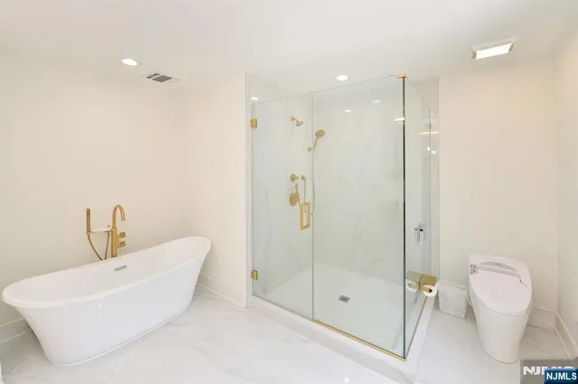 a bathroom with a bathtub shower sink mirror and toilet