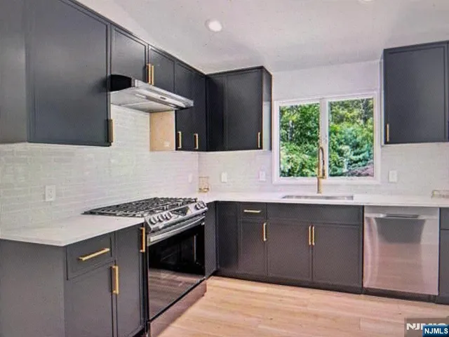 a kitchen with stainless steel appliances granite countertop a stove a sink and a microwave
