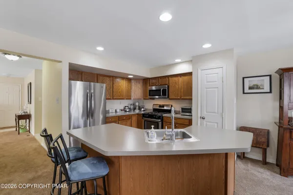 a kitchen with stainless steel appliances granite countertop a dining table chairs and refrigerator