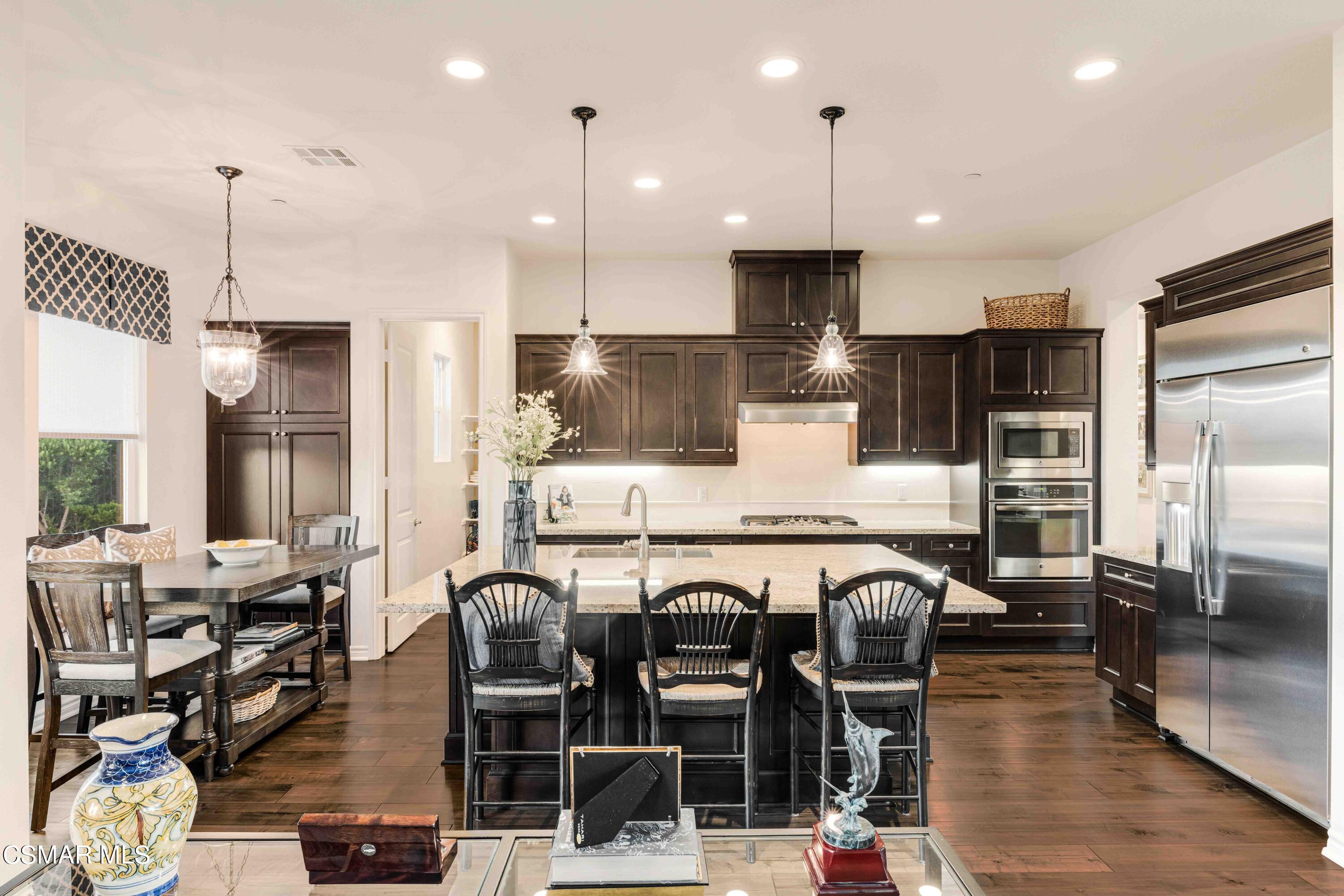 13210 Bent Grass Place Moorpark, CA 93021 - Photo 11 of 73 a kitchen with stainless steel appliances kitchen island granite countertop a table chairs and a refrigerator