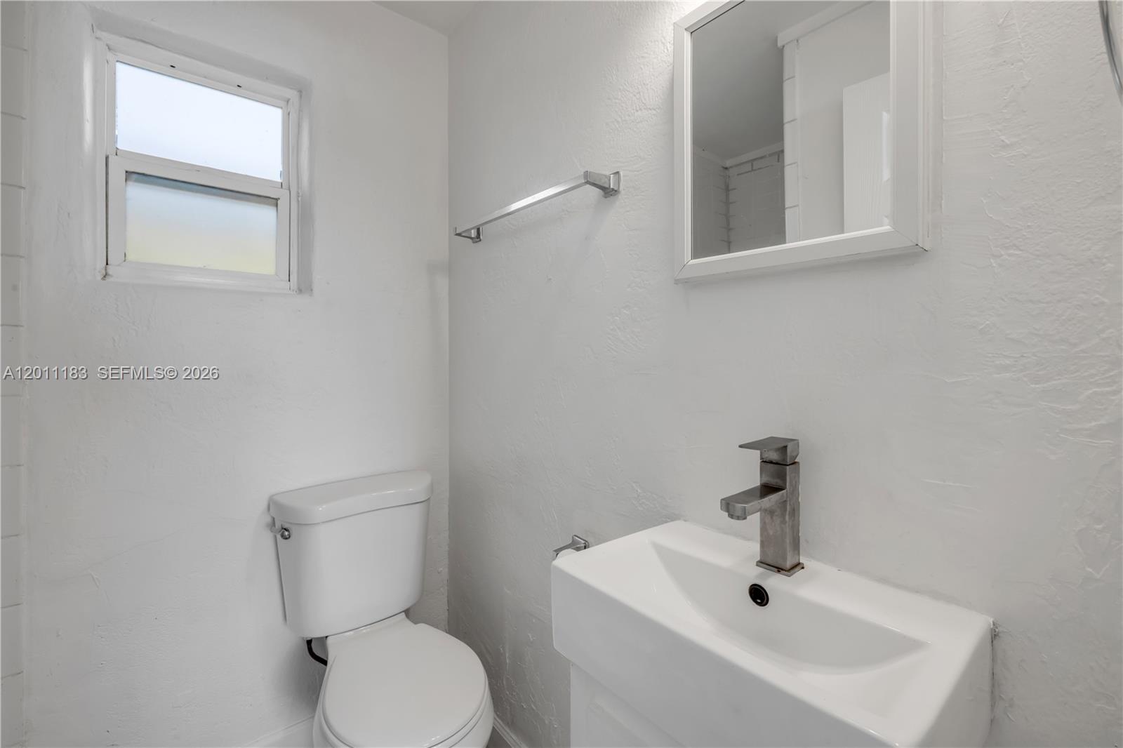 1208 South Ridgewood Avenue Daytona Beach, FL 32114 - Photo 12 of 27 a white toilet sitting next to a bathroom sink