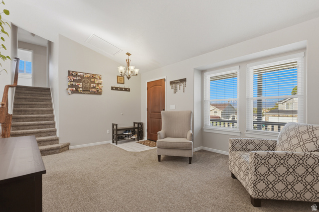 11189 Ohenry Road East Sandy, UT 84070 - Photo 6 of 44 Carpeted living area featuring a wood-panel entry door, a multi-light chandelier, and staircase with wood railing