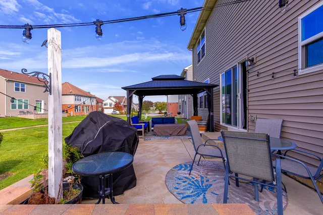 a view of a patio with table and chairs under an umbrella with a barbeque