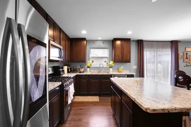 a kitchen with stainless steel appliances granite countertop sink stove refrigerator and cabinets