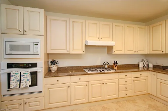 a kitchen with granite countertop white cabinets and white appliances