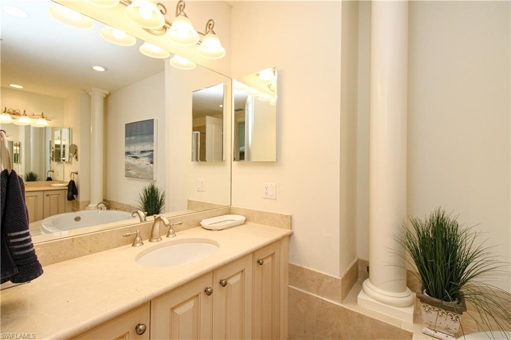 2713 Callista Court, Unit 103 Naples, FL 34114 - Photo 29 of 47 a bathroom with a sink a large mirror and a shower