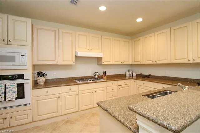 a kitchen with granite countertop white cabinets and white appliances