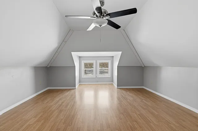 an empty room with wooden floor chandelier fan and windows