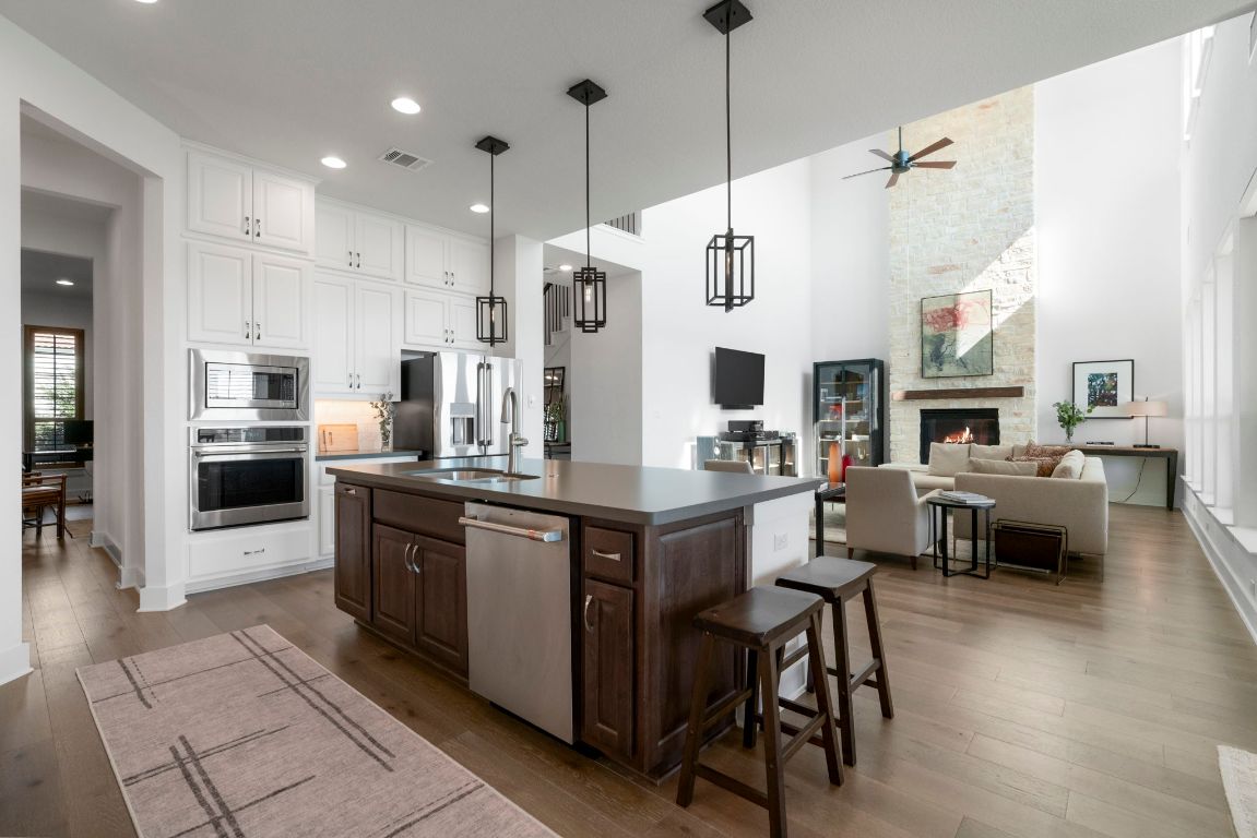 4704 Montorio Way Leander, TX 78641 - Photo 39 of 40 a large kitchen with stainless steel appliances kitchen island granite countertop a table chairs and a refrigerator