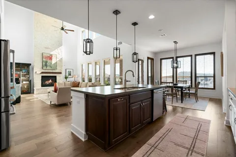 a spacious kitchen with stainless steel appliances granite countertop a sink counter space and living room view