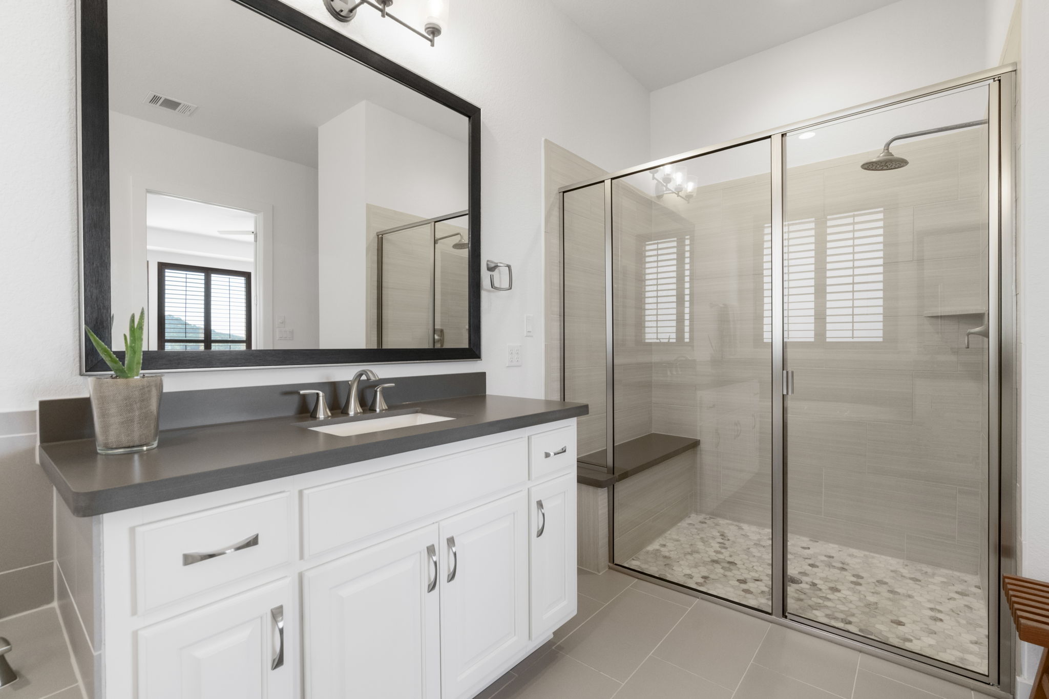 4704 Montorio Way Leander, TX 78641 - Photo 19 of 40 a bathroom with a granite countertop sink a mirror and a shower
