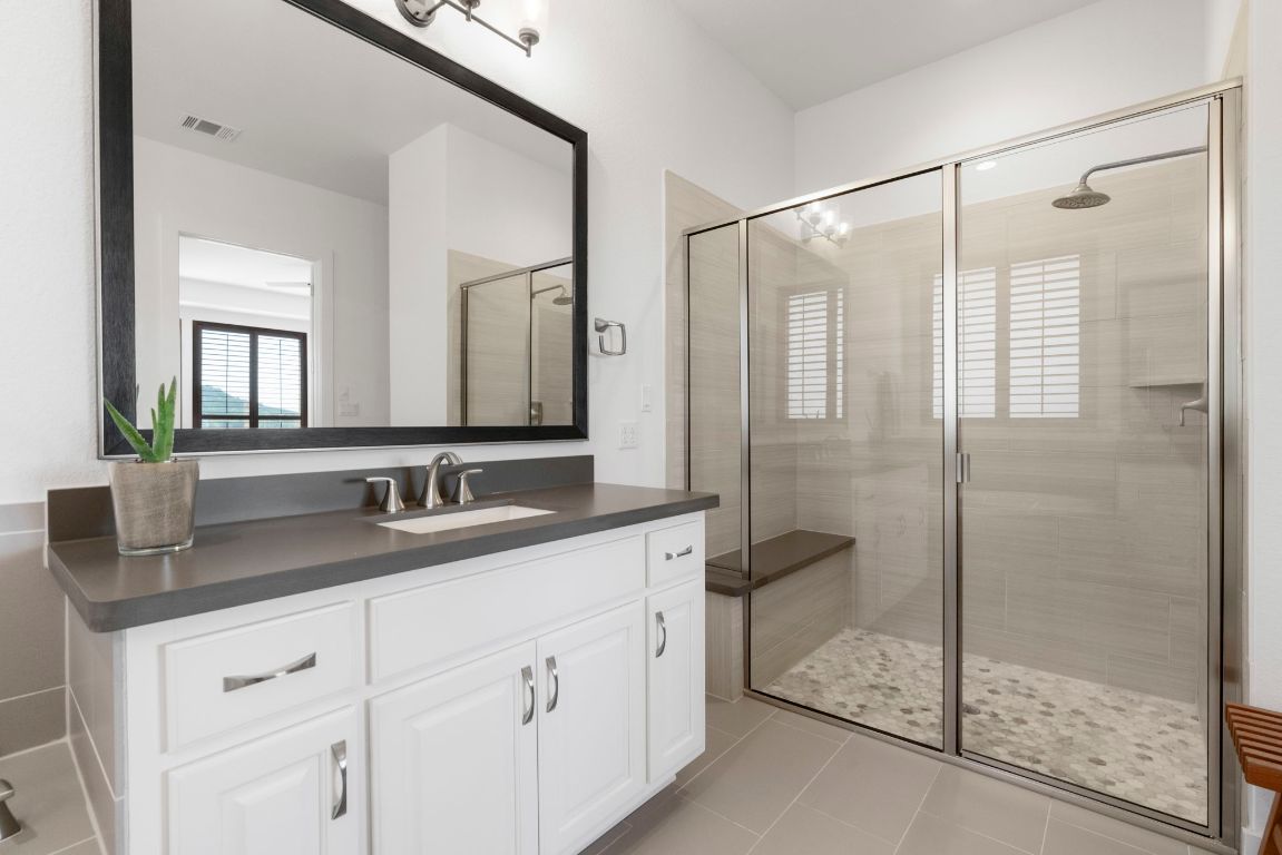 4704 Montorio Way Leander, TX 78641 - Photo 19 of 40 a bathroom with a granite countertop sink a mirror and a shower