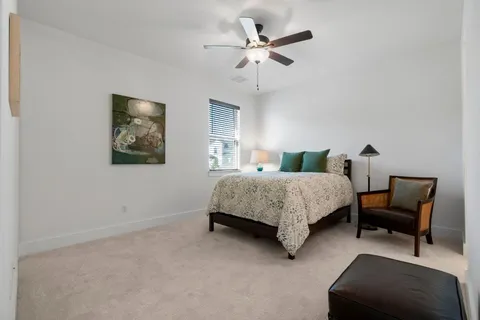 a bedroom with a bed a chair and a potted plant on a dresser