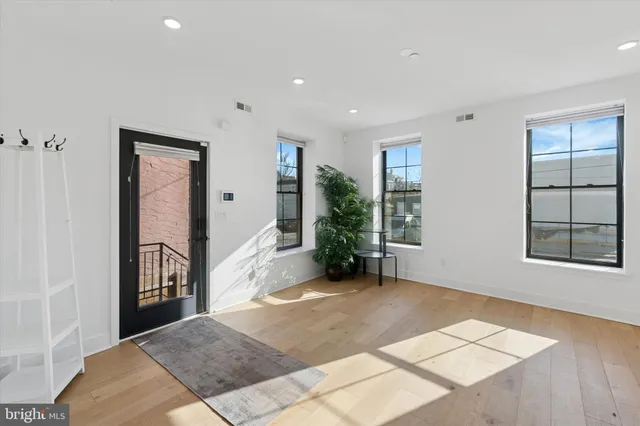 a view of an empty room with window and wooden floor