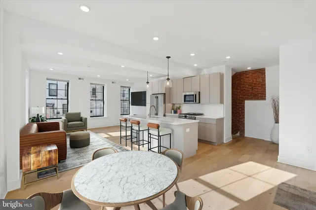 a living room with stainless steel appliances kitchen island granite countertop a dining table chairs and a kitchen view